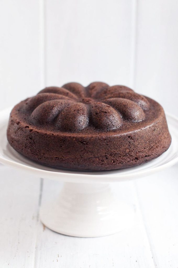 chocolate pound cake baked in bundt tin on white cake stand