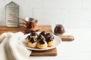 profiteroles with chocolate sauce on white plate