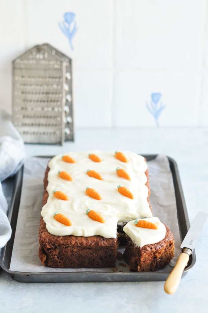 carrot cake on baking tray with vintage knife and vintage graters in background
