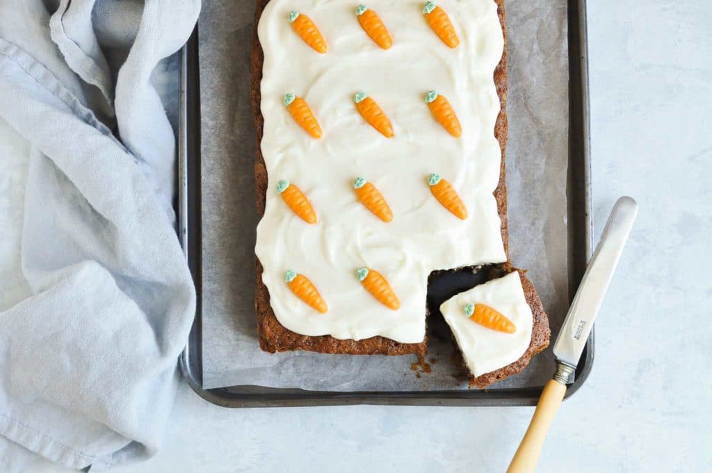 slab of carrot cake on baking tray with blue tea towel