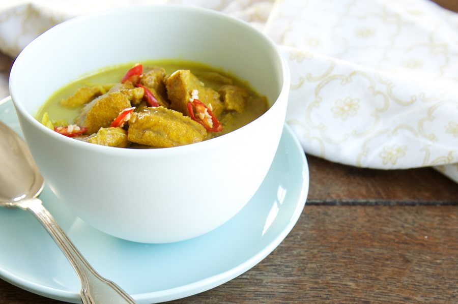 keralan fish curry in blue bowl with spoon