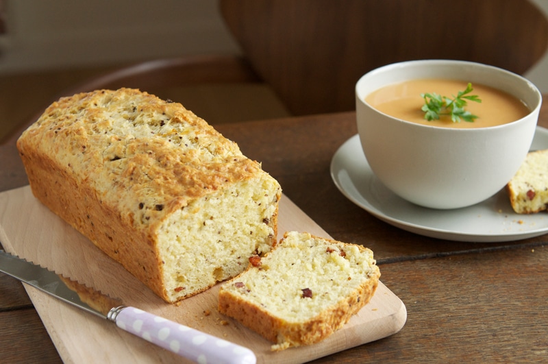 bacon and cheese savoury cake on wooden board with bowl of soup