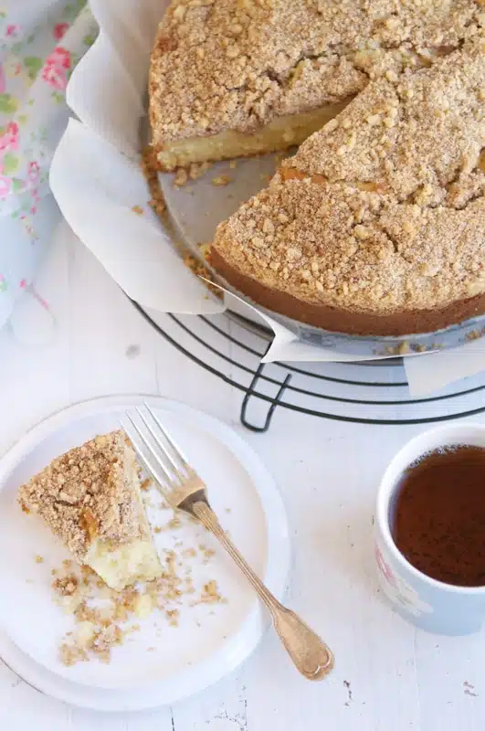 apple crumble cake on wire rack with cup of tea
