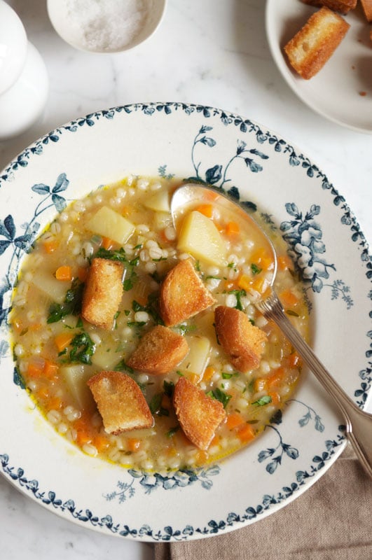 vegetable barley soup with croutons in bowl with blue pattern