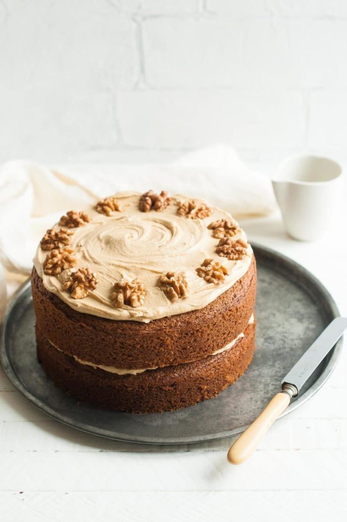 coffee and walnut cake on tray with knife and white tea towel in the background