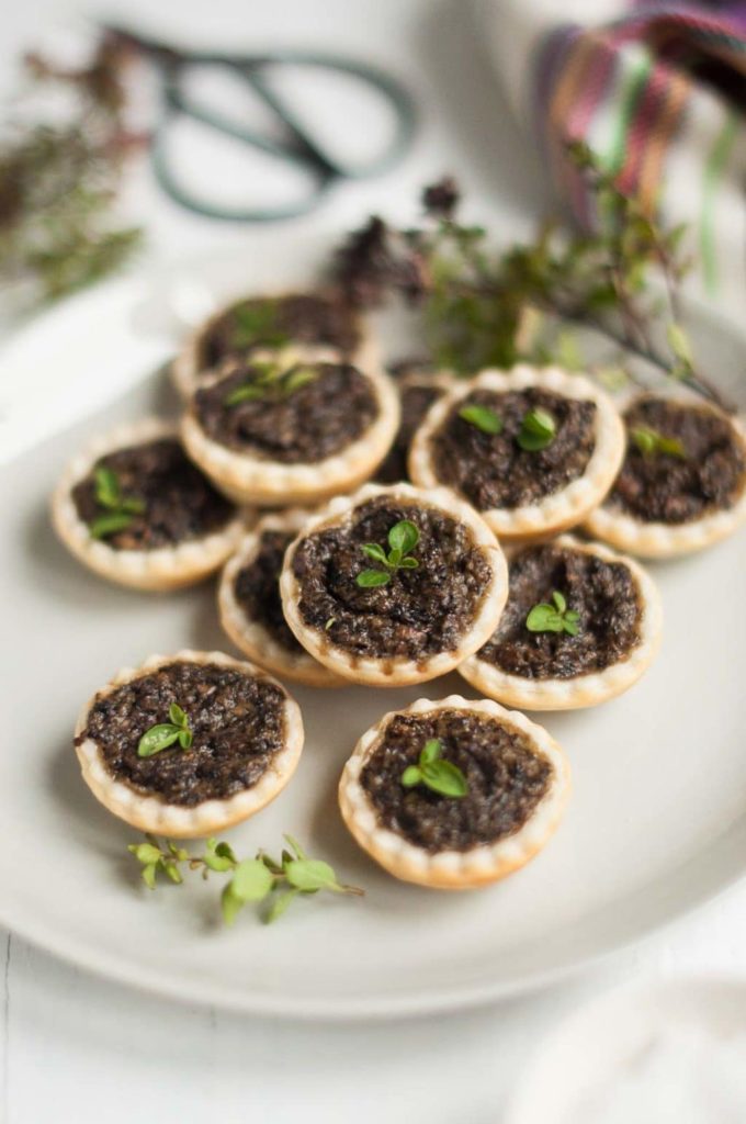 mushroom tarts on plate with small herbs and garden scissors in background