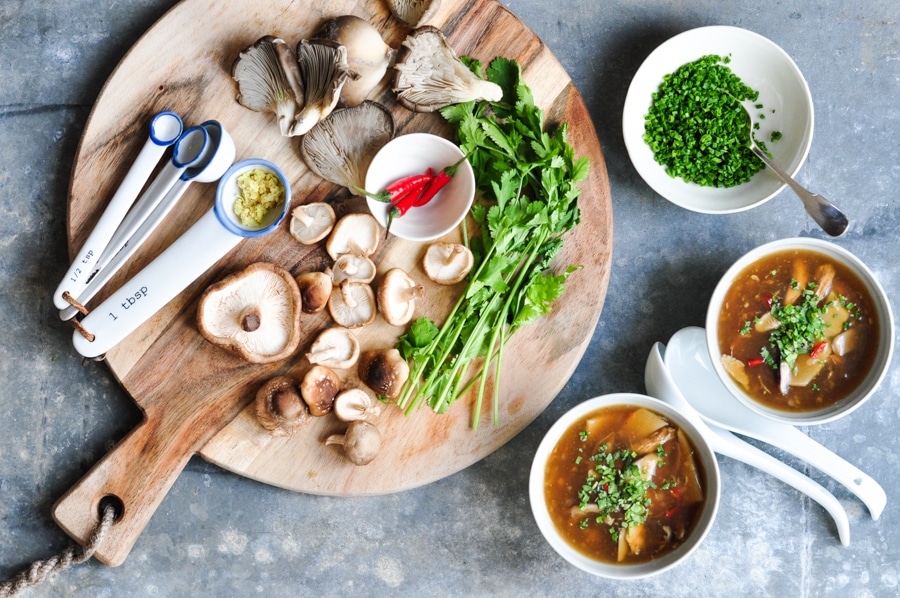 hot and sour soup with fresh mushrooms on chopping board
