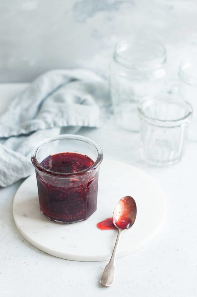 strawberry jam in glass jar on marble plate