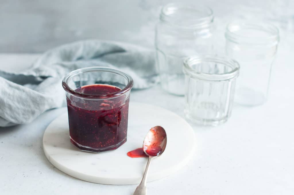 strawberry jam with empty glass jars in background