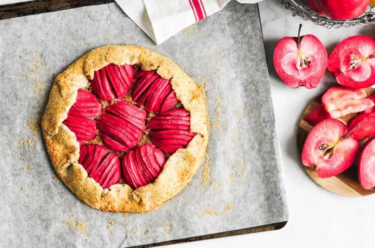 apple galette on baking tray with red apples