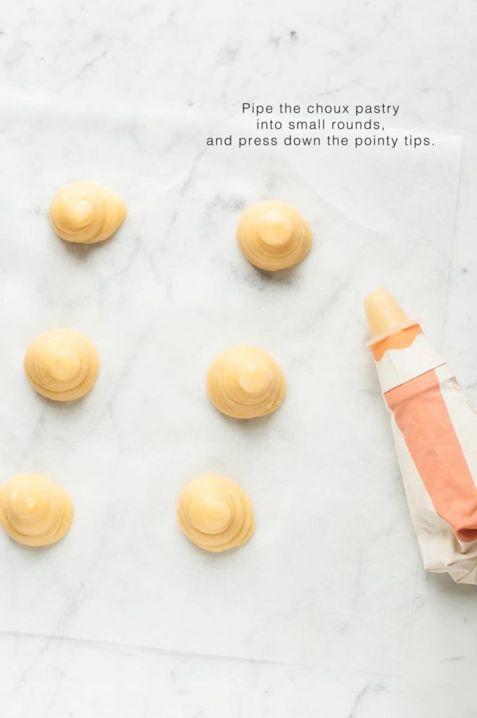 how to make profiteroles, pipe the choux pastry into small rounds using a piping bag