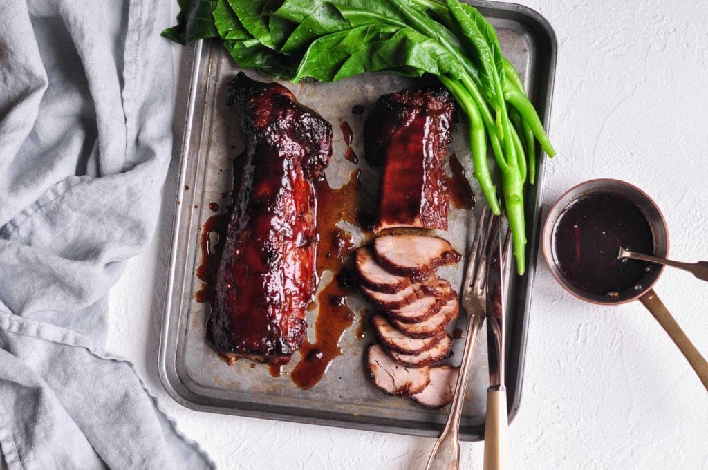 char siu pork on metal tray with bok choy and knife and fork
