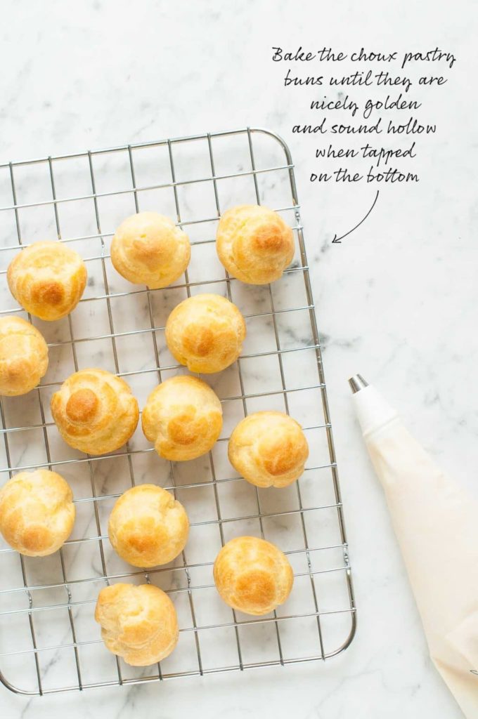 baked choux buns on wire rack with piping bag
