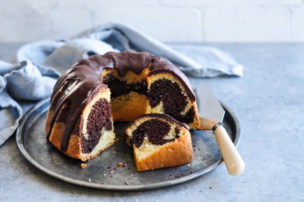 sliced marble cake on metal tray with cake knife and blue napkin