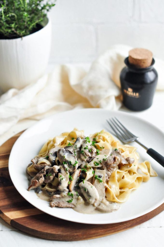beef stroganoff with pasta on plate with black fork