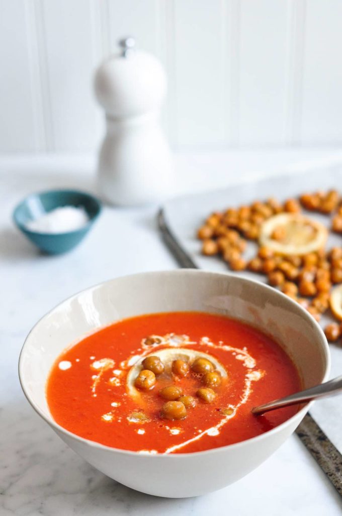 cream of tomato soup in bowl topped with roasted chickpeas and swirl of cream