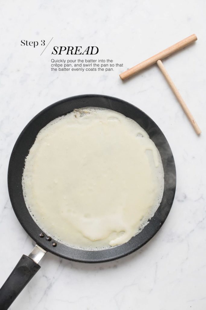 crepe batter on non-stick pan with wooden rake