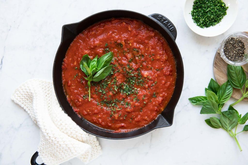marinara sauce in skillet with chopped herbs