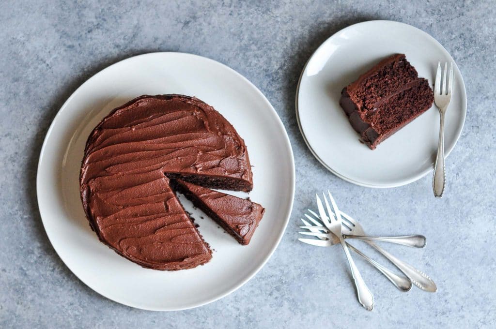 sour cream chocolate cake on plate with a slice on smaller plate with vintage forks