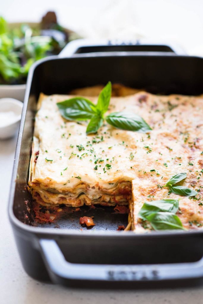 spinach lasagna in black baking dish with slice cut out