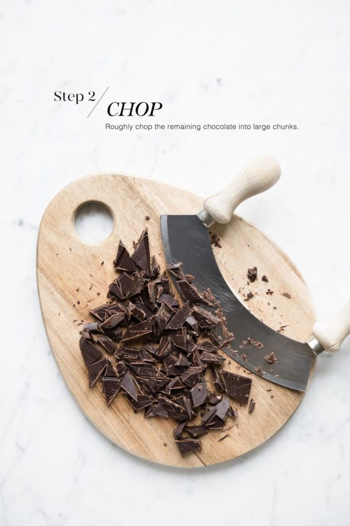 chopped dark chocolate on wooden board with mezzaluna knife