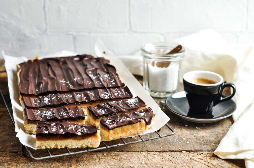 chocolate caramel slice on wire rack with coffee