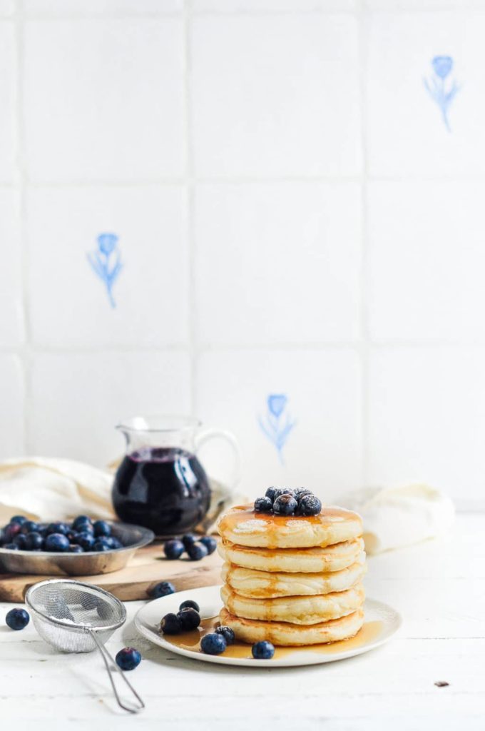 easy fluffy pancakes with glass jug of blueberry syrup
