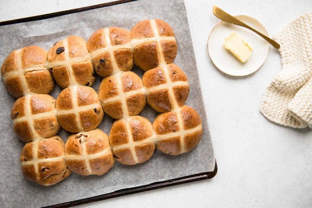 hot cross buns on baking tray with plate of butter