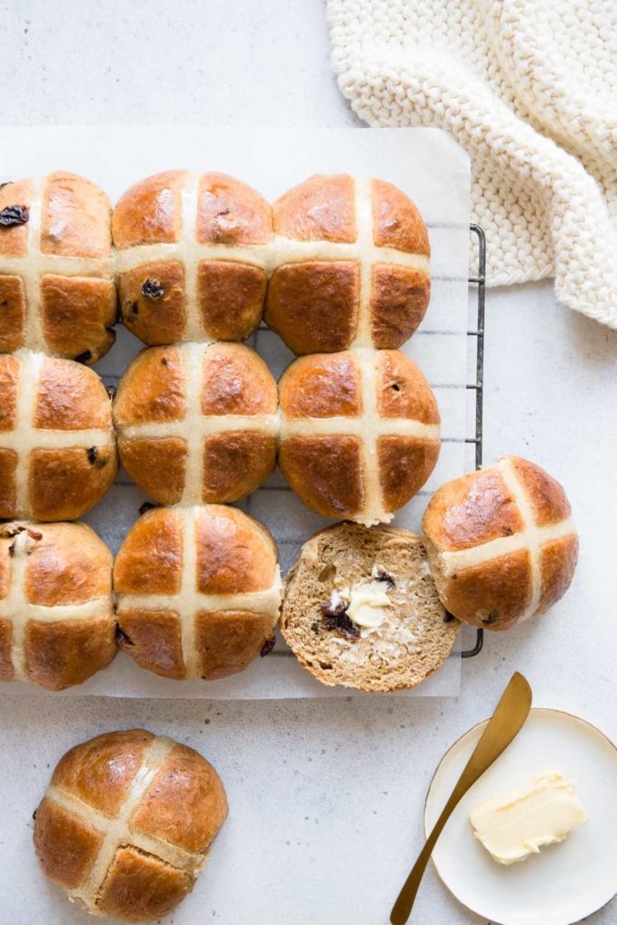 hot cross buns on wire rack with small plate of butter with gold butter knife