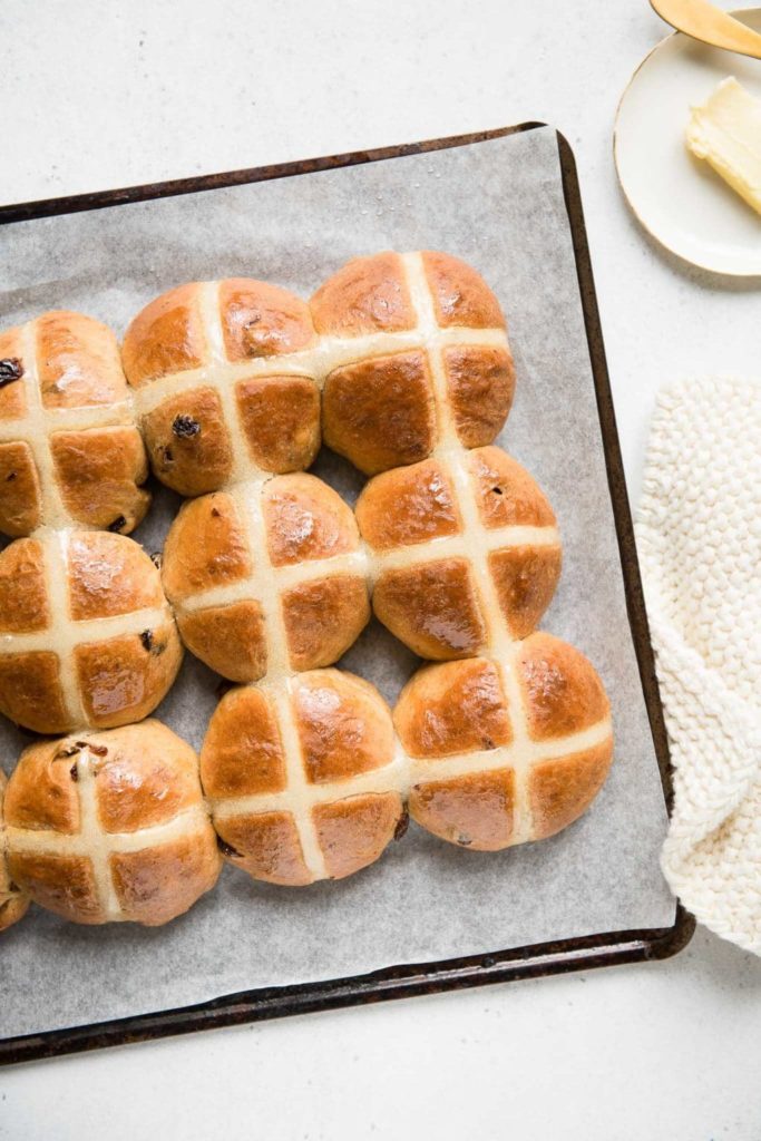 hot cross buns on baking tray with white cloth