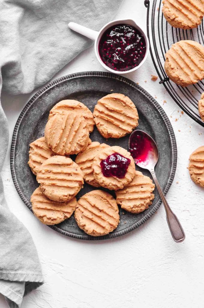 soft peanut butter cookies on metal plate with spoonful of raspberry jam