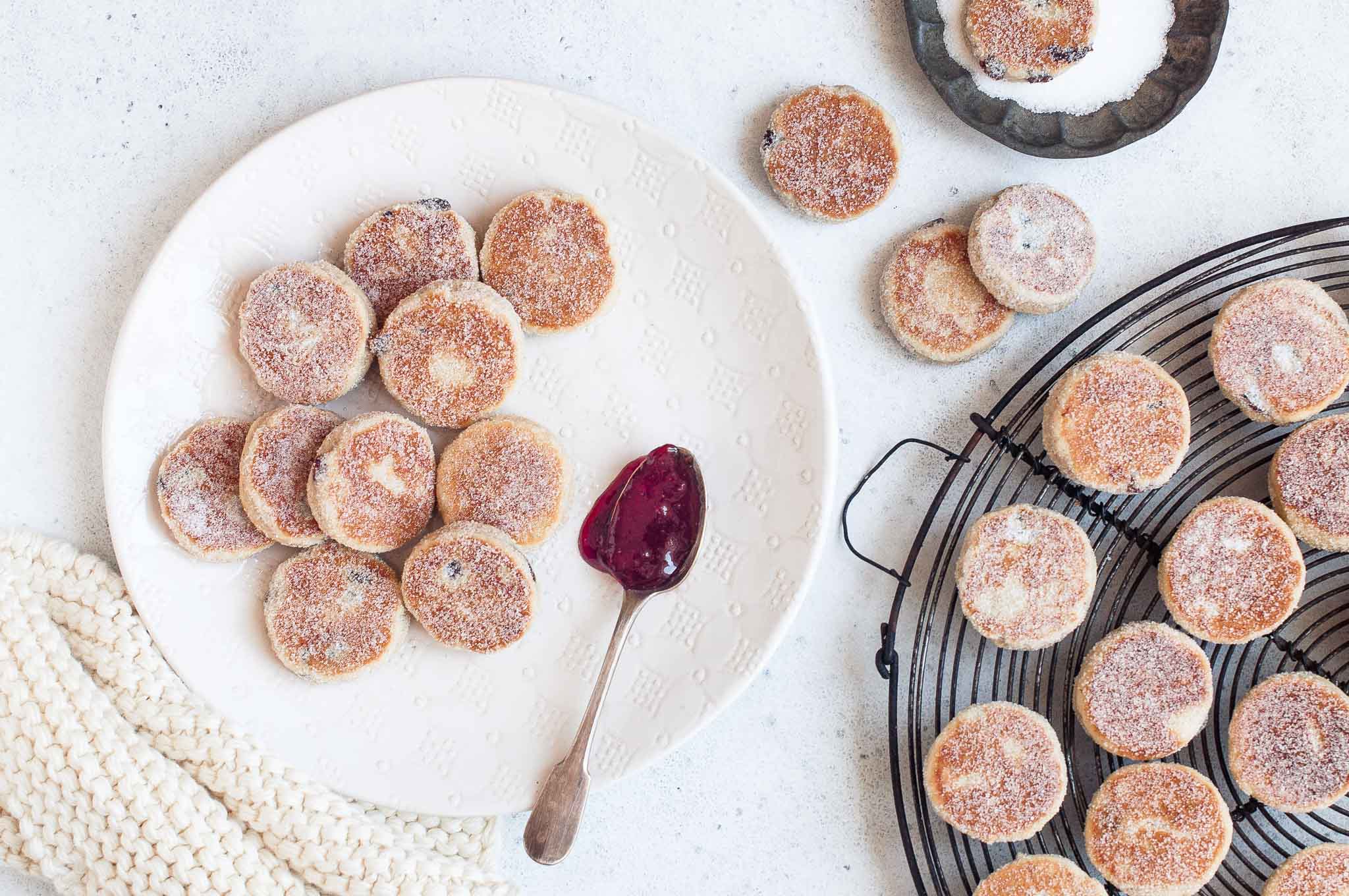 welsh cakes sprinkled in sugar on white plate and metal wire rack