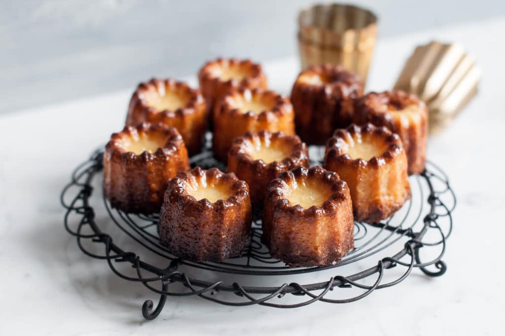 canneles on wire rack with copper moulds in background