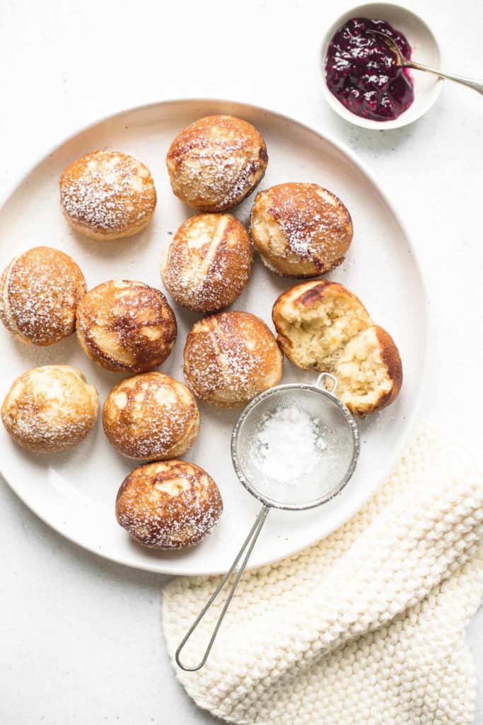 white plate with aebleskivers dusted with icing sugar