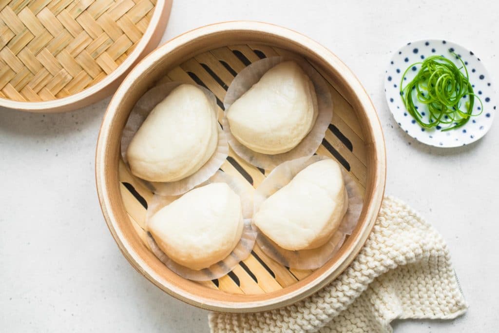 four bao buns in steamer basket