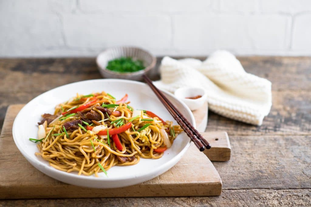 yakisoba noodles on white plate with chopsticks