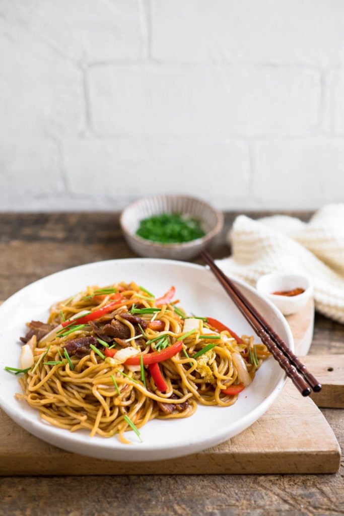 yakisoba noodles on white plate on wooden board
