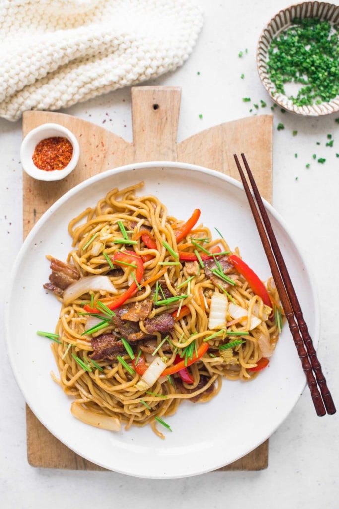 yakisoba noodles on white plate on wooden board with white cloth
