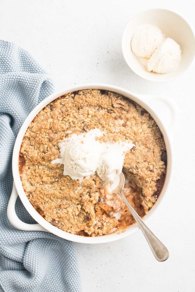 apple crumble in pie dish with two scoops of ice-cream