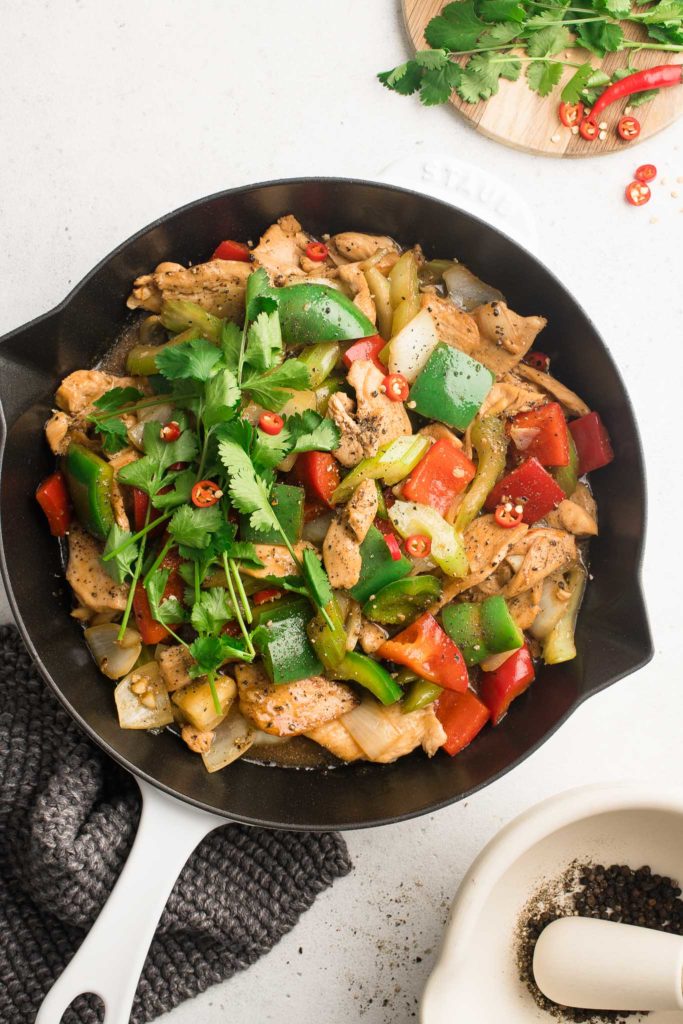 black pepper chicken in skillet with mortar and pestle