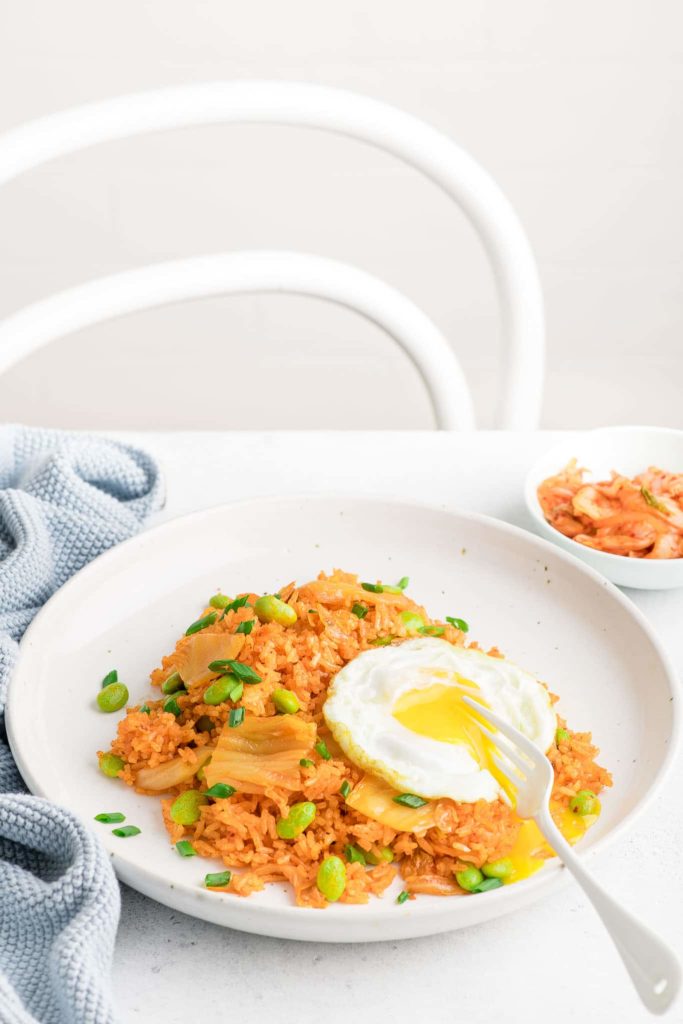 kimchi fried rice in white bowl with fried egg with runny yolk