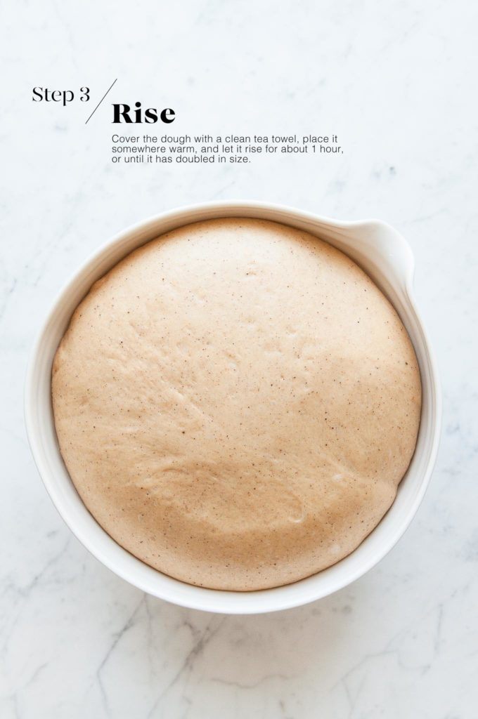 risen dough for hot cross buns in white mixing bowl