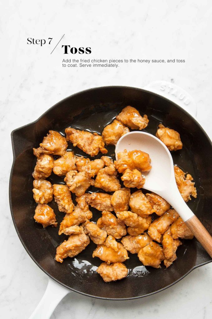 honey chicken in skillet with white spoon