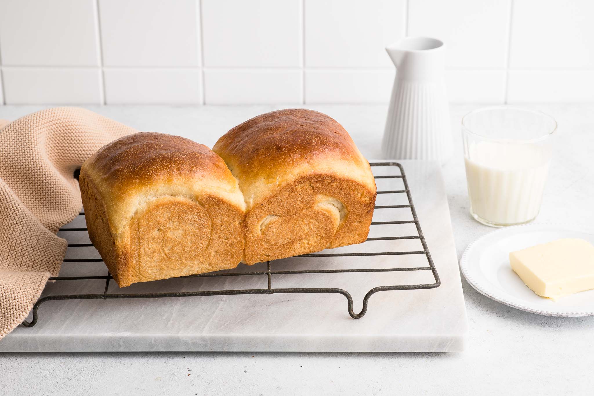 milk bread loaf on wire rack with glass of milk