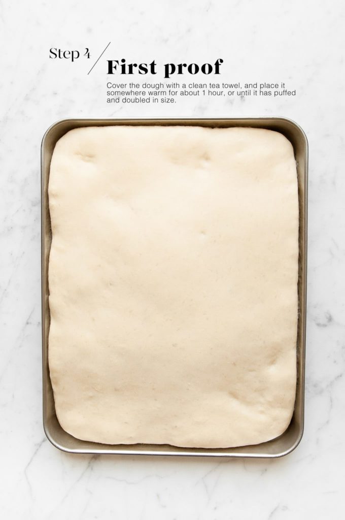risen focaccia dough in baking tray