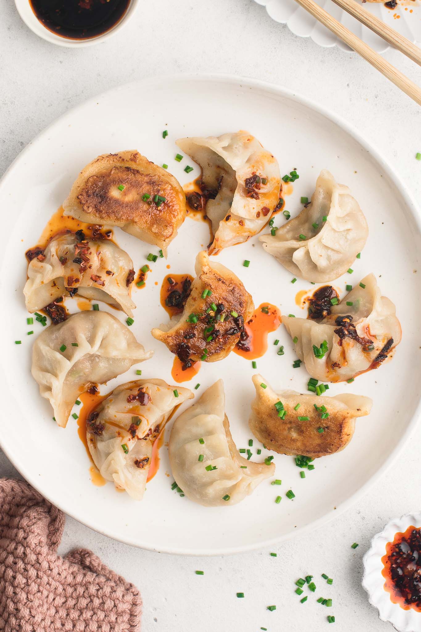 pork potstickers with chilli oil and herbs on white plate