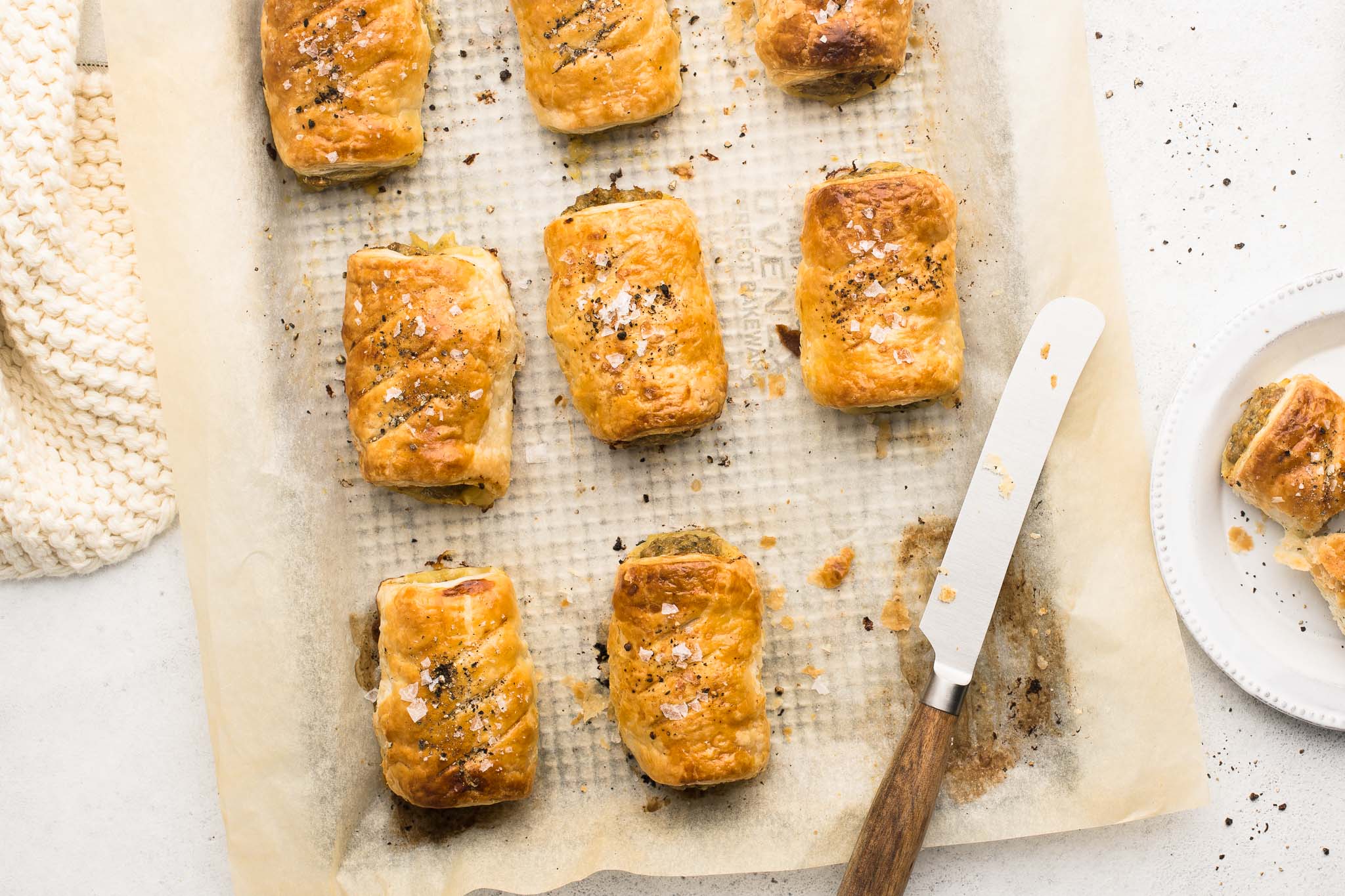 pork sausage rolls with knife on baking tray