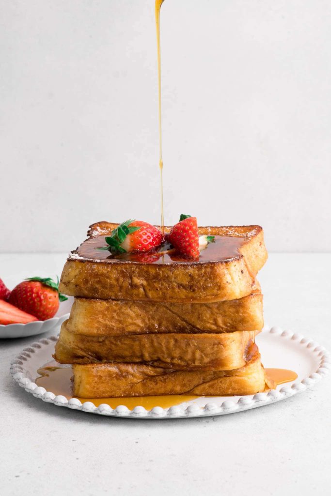 stack of french toast on plate with maple syrup