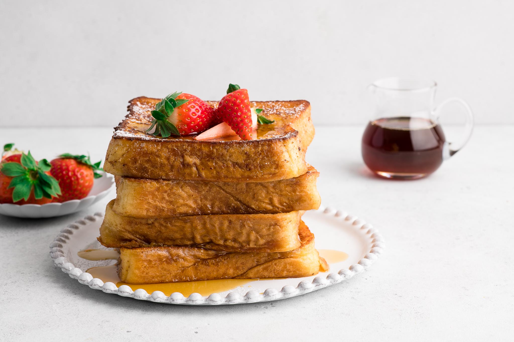 plate of french toast with strawberries and maple syrup
