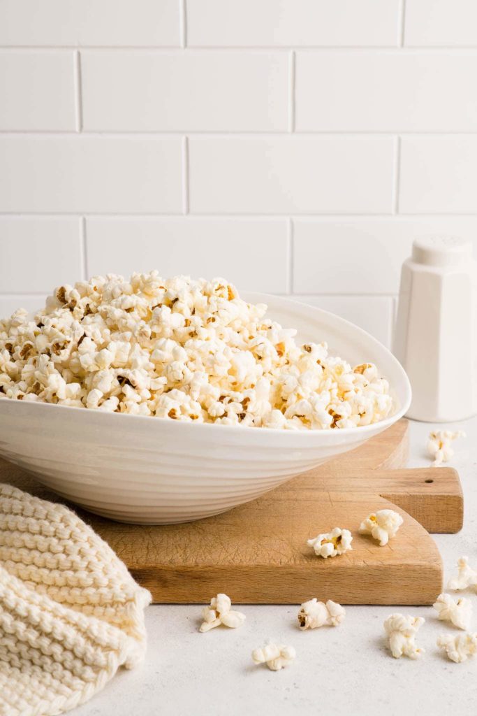 white bowl full of popcorn on wooden board